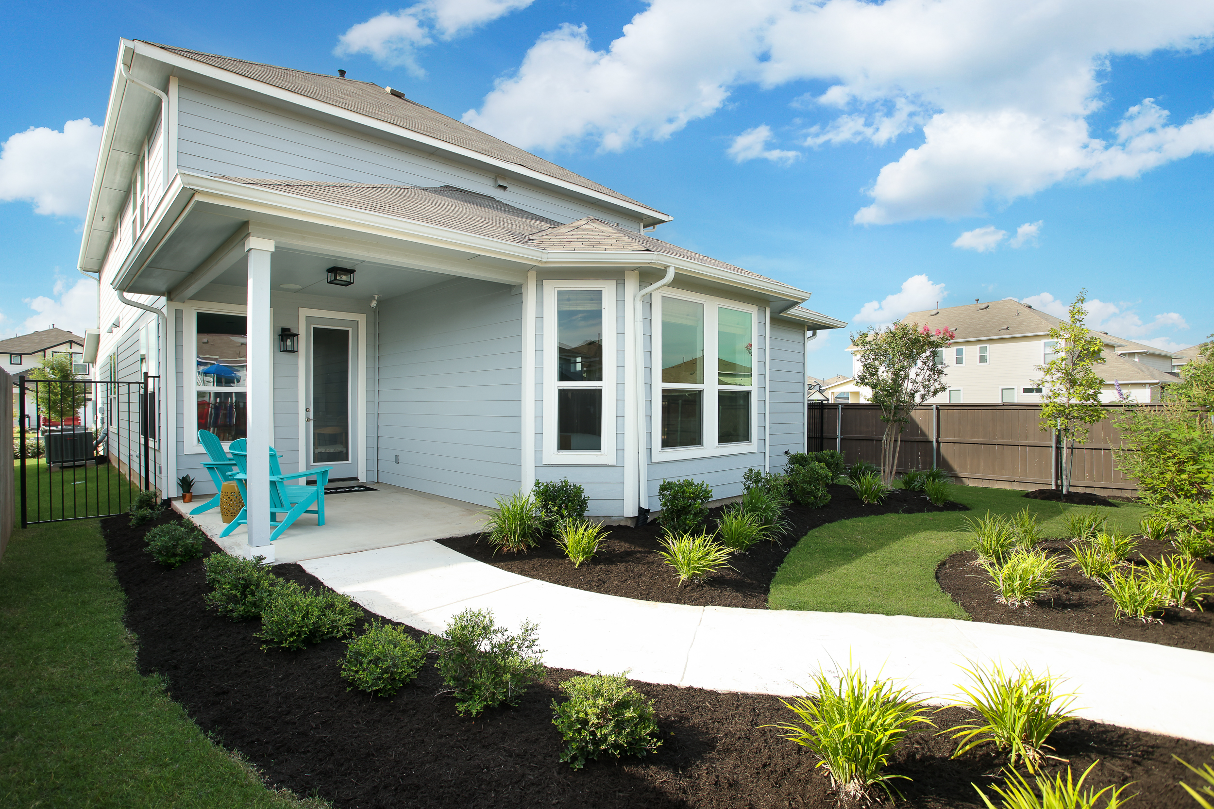 Front exterior of blue one-story home with a side walk and landscaping.