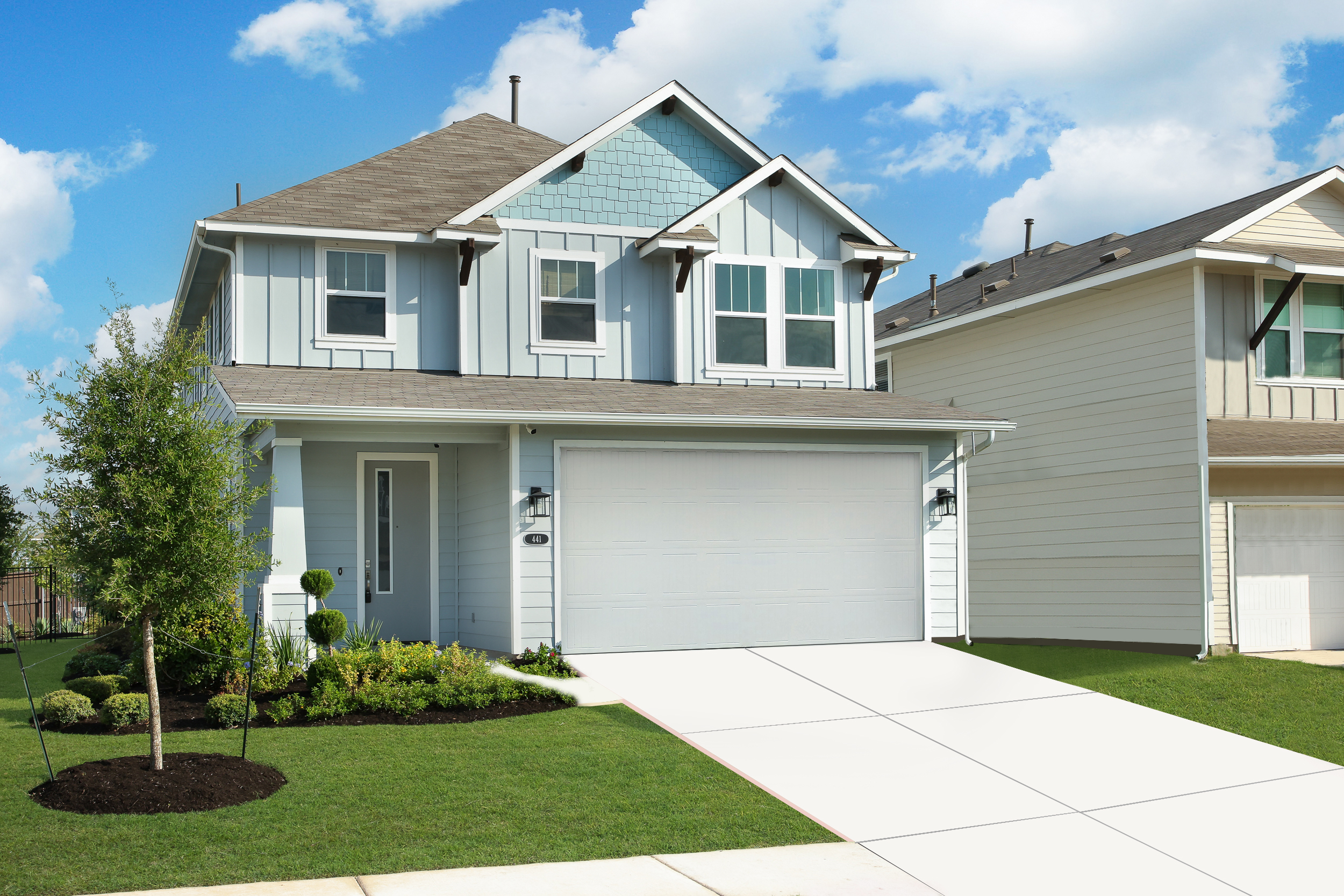 Exterior image of two-story blue home with green grass and a driveway