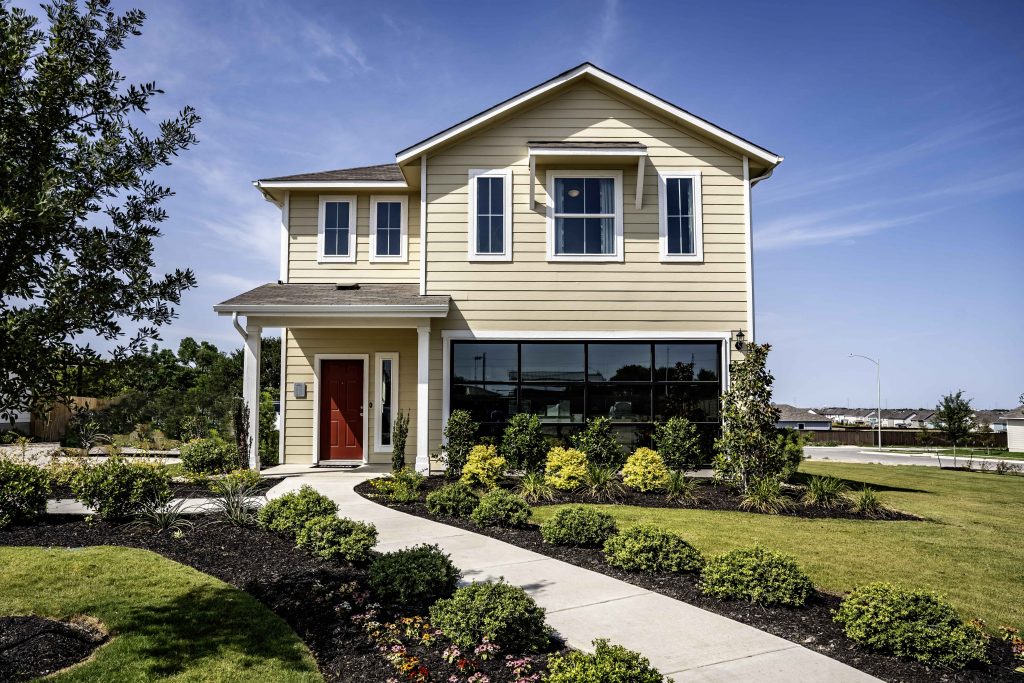 Front exterior photo of two-story model home with a sidewalk leading up to the red front door.